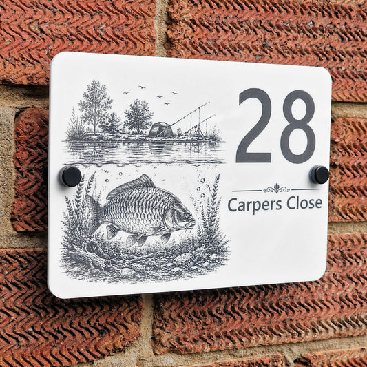 Angled view of personalised acrylic carp fishing house number sign mounted on a brick wall, showing detailed laser engraving and black standoff fixings.