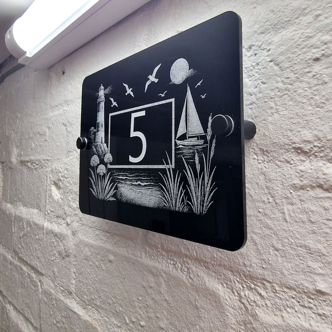 Engraved Coastal Scene House Number Sign with Lighthouse & Seaside Details – Black Acrylic with Stand-Offs - Right Angled View