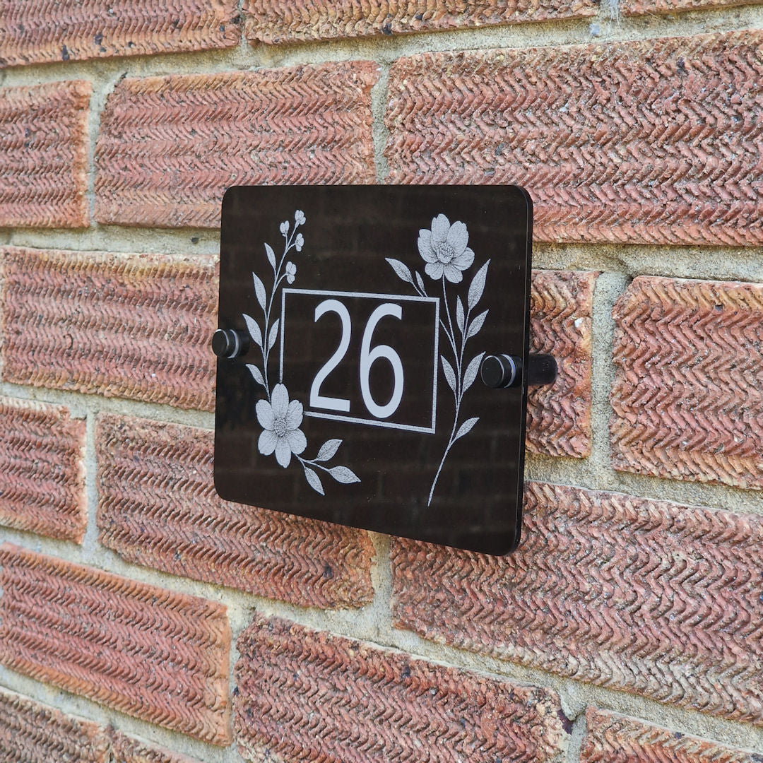 House number sign with floral side blooms design on a brick wall