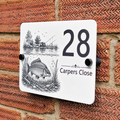 Side-angle view of personalised acrylic carp fishing house number sign on a brick wall, showing the engraved house number and floating plaque design.