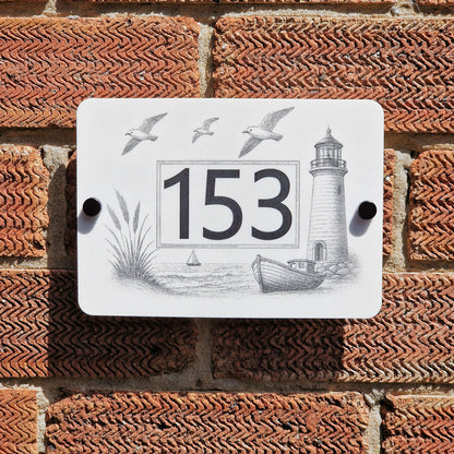 Decorative house number sign with lighthouse design on a brick wall