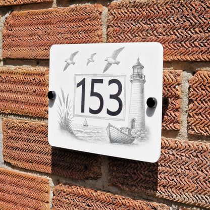 Decorative house number sign with lighthouse design on a brick wall