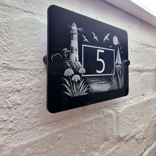 Engraved Coastal Scene House Number Sign with Lighthouse & Seaside Details – Black Acrylic with Stand-Offs - Left Angled View