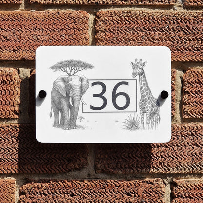 Decorative house number sign with elephant, giraffe, and tree design on a brick wall.