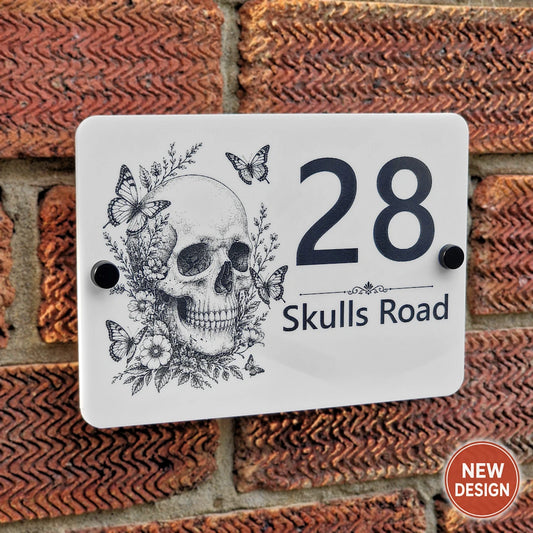 Personalised Skull & Butterfly house number sign mounted on a brick wall, laser engraved on white acrylic with black stand-off fixings.